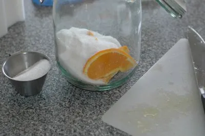 Sukker og appelsinbåde hældes i sylteglasset.